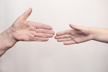 The hands of an adult and a child are stretched out to each other, but do not touch each other in order to prevent viruses, bacteria and microbes.