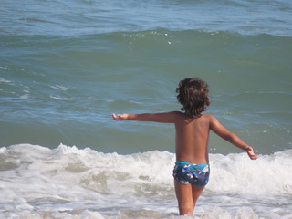 Child with open arms when entering the sea