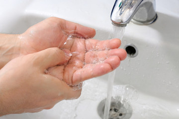 Washing hands with soap under the faucet with water. Hygiene concept.
