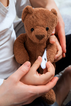 mother and child measure the temperature of the teddy bear. Fever Concept. treatment is fun. medical education concept.