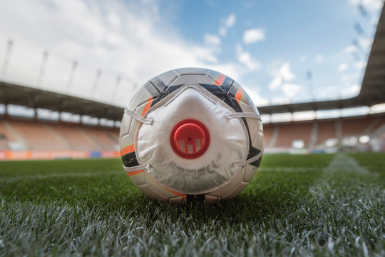 The ball with mask (symbol coronavirus) in the corner of soccer pitch.