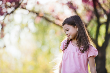 Small girl standing outside in spring nature. Copy space.