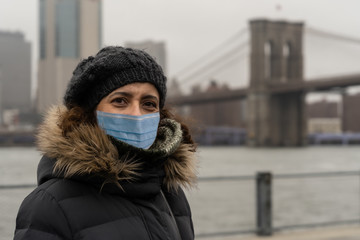 Woman wearing surgical mask with warm clothes in Dumbo neighborhood.Concept of Coronavirus, COVID-19 and quarantine