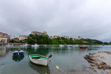Fototapeta na wymiar San Vicente de la Barquera, small medieval town in Cantabria, (Spain). Scenic mountain and sea landscape in the north of Spain, with green meadows and boats in a beautiful setting.