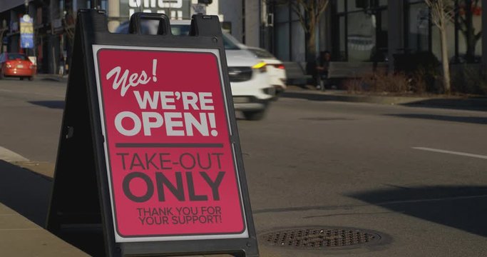 A sign in the business district of a large city reads that a cafe is open for take-out only. Take-out became the default way of business for restaurants during the Coronavirus outbreak of 2020.  	