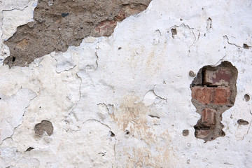 Old weathered painted white background texture. Brick wall with old falling plaster.