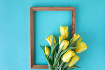 Beautiful flower arrangement. Yellow flowers tulips, empty frame for text on a blue background. Wedding. Birthday Valentine's Day. Mothers Day. Flat lay, top view, copy space
