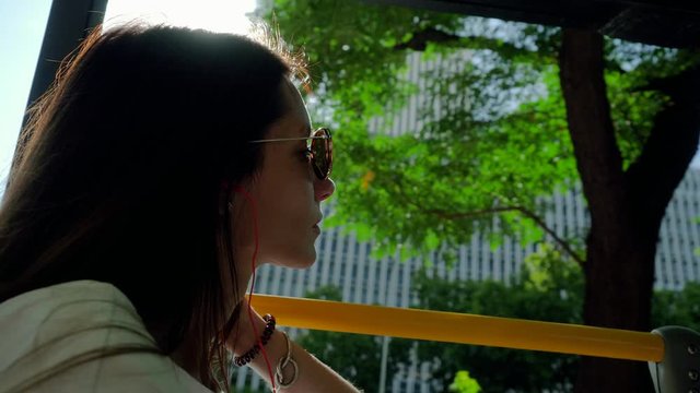 Close up of young beautiful woman looking at the sights of Madrid while riding around the city on a tour bus on summer sunny day. Spain. 4K