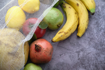 Fresh organic fruits and vegetables in reusable textile shopping bags.