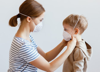 Mother putting on medical mask on son.