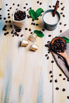 Coffee beans on vintage light wooden table, with coffee capsule and a cup of coffee. Top view. Copyspace.
