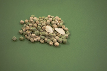 many seeds peas and two seeds of pumpkin  on a green background
