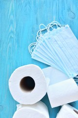roll of toilet paper and sterile protective masks with selective focus on blue wooden background. toilet paper and face mask for Covid-19 pandemic. Increased potential. high demand. Vertical position