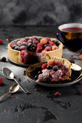 Homemade cheesecake with raspberries, blackberries and currants with karkade tea on black background