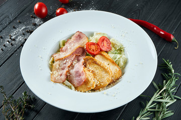 Caesar salad with croutons, parmesan, bacon, chicken, egg in whte bowl on white background. Restaurant serving. Close up with copy space.