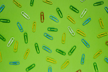Multicolored paper clips on a green background. Back to School Concept