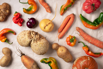 Trendy ugly organic vegetables. Assortment of fresh eggplant, onion, carrot, zucchini on green background. Top view. Cooking ugly food concept. Non gmo vegetables