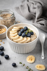 oatmeal with blueberries and banana in a white bowl on a light background. Top view. Breakfast