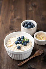 oatmeal with blueberries and banana in a white bowl on a  wooden background. Top view. Breakfast