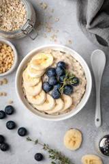oatmeal with blueberries and banana in a white bowl on a light background. Top view. Breakfast