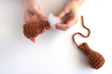 Children’s toy from plush yarn creation process. Filling the paw of a bear toy with filler. There...