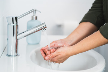 Hygiene. Cleaning Hands. Washing hands with soap. Young woman washing hands with soap over sink in...