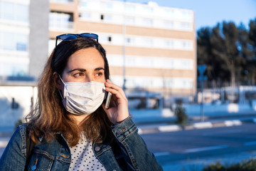 young woman with a respirator on the street with her smart phone