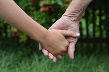 granddaughter and grandmother holding hands outdoors close up 