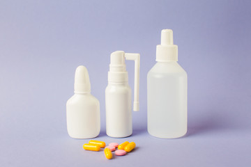 Spray for the nose, a remedy for sore throat, antiseptic. White Vials with medicines on a lilac background.