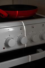 Empty red pan stands on a white electric stove