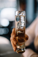 Bartender holding on his hand gin and tonic cocktail in a highball glass. Smooth image with shallow depth of field. 