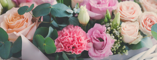 Pastel trend colored flowers in white basket isolated, selective focus
