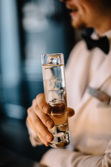 Bartender holding on his hand gin and tonic cocktail in a highball glass. Smooth image with shallow depth of field. 