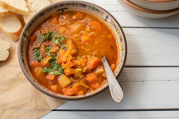 Vegan lentil and vegetables  soup bowl on wooden table