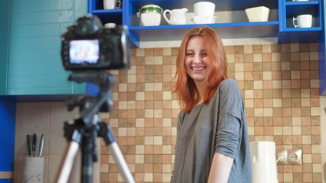 Food blogger girl influencer is recording a video or podcast in the kitchen. Makes lifestyle blog vlog about healthy and unhealthy foods. A woman communicates with subscribers, Shows dislike hands.