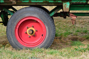 Fototapeta na wymiar Detail of an old agricultural vehicle, with a red old wheel and tires, on a meadow