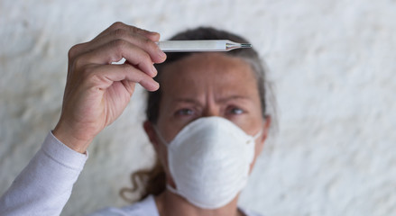 adult woman with thermometer and chinstrap in prevention of influenza virus and coronavirus