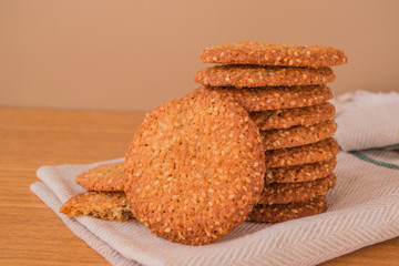 Closeup stack of homemade cookies with sesame on wooden table, selective focus.