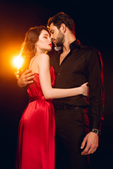 Side view of elegant girl embracing handsome boyfriend on black background with lighting