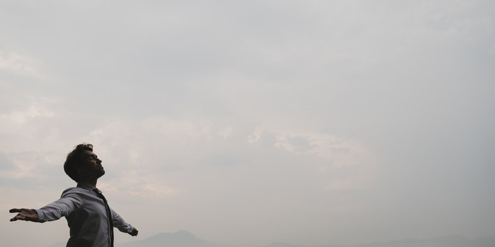 Businessman Standing Under Grey Cloudy Sky