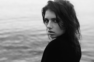 close portrait , black and white natural photo of an elegant girl walking along the beach, fashion session in natural light, analog style
