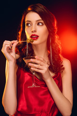 Elegant woman holding stick with olives and glass of cocktail on black background with lighting