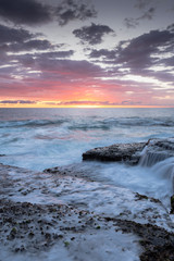 Seascape with sunrise over the ocean and water flowing across the rocks