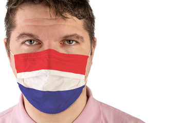 Portrait of adult caucasian man who wears protective mask on his face against influenza and protect health from bacteria. Flag of Netherlands.