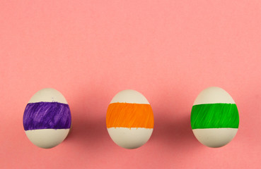 Easter concept with three colored eggs against a pink background, each of which has its own pattern
