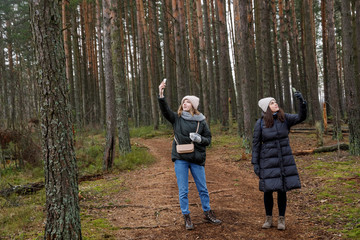 Search in the woods for telephone communication. 2 girls with gadgets trying to catch internet connection