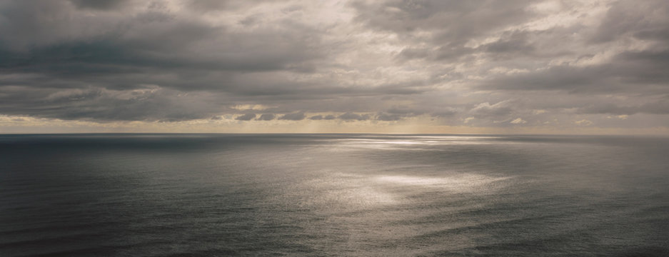 Storm clouds clearing over expansive ocean, dappled sunlight on water, northern Oregon coast,Clearing storm clouds and dappled sunlight on vast ocean at dusk