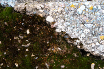 The surface of an old concrete block with traces of blue paint and yellow deprive in one part and...