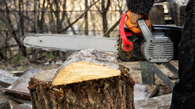 Woodcutter sawing a board with a chainsaw