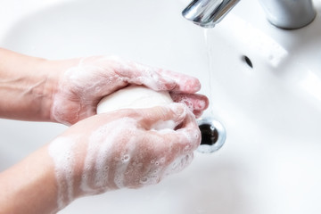 Washing hands with soap under the faucet with water